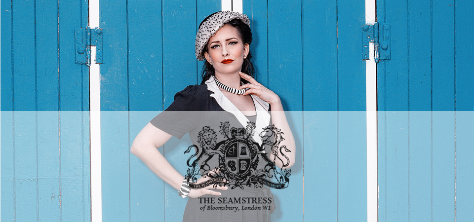 Seamstress of Bloomsbury Eine Frau trägt ein schwarz-weißes Kleid und einen Hut im 40er Jahre Stil, Logo der Marke Seamstress of Bloomsbury