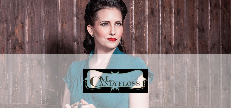Miss Candyfloss Frau trägt petrolfarbenes Kleid im 50er Jahre Stil, Logo der Marke Miss Candyfloss