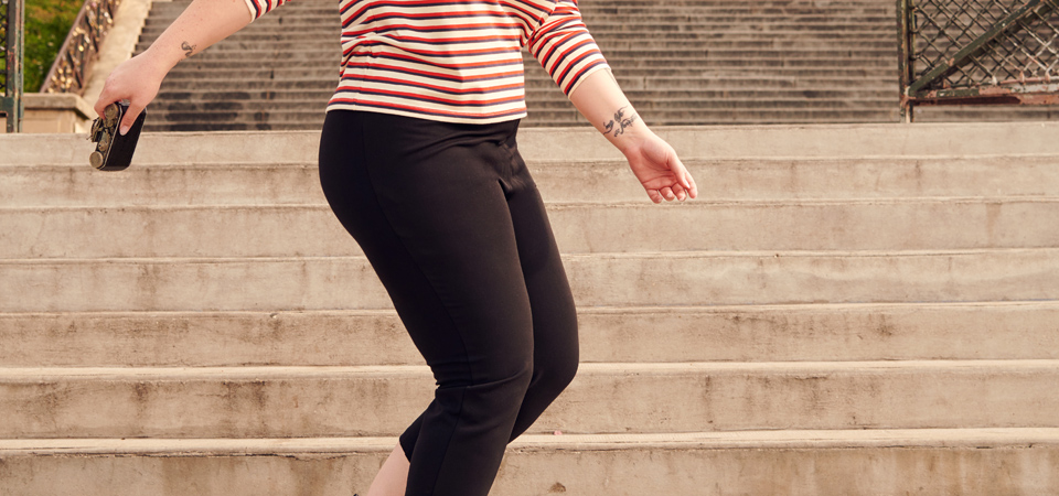 Caprihosen Eine Frau in einer engen schwarzen Hose geht eine Treppe herunter
