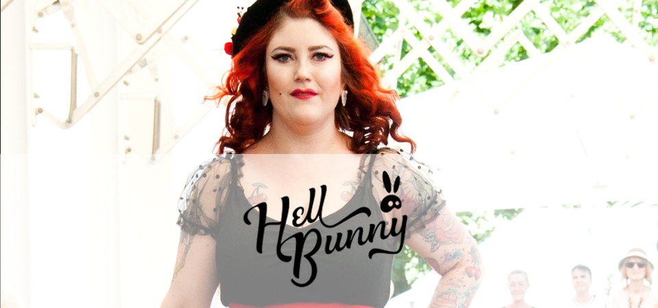 Hell Bunny Frau in einem schwarzen Oberteil mit Tüllärmeln, Logo der Marke Hell Bunny