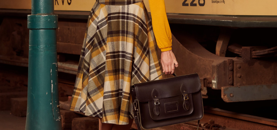 Vintage-Röcke Eine Frau in einem karierten Winterrock im 50er Jahre Stil steht an einer Straßenlaterne