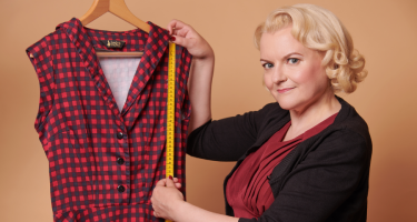 Größen finden Eine Frau hält ein Maßband an ein Kleid